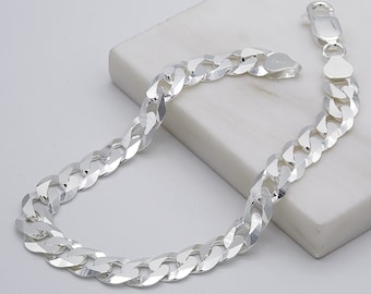May include: A silver curb chain bracelet with a polished finish. The chain is made of interlocking links that are flat and rectangular in shape.