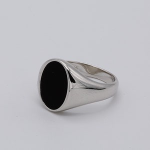 May include: A silver signet ring with a black oval gemstone.
