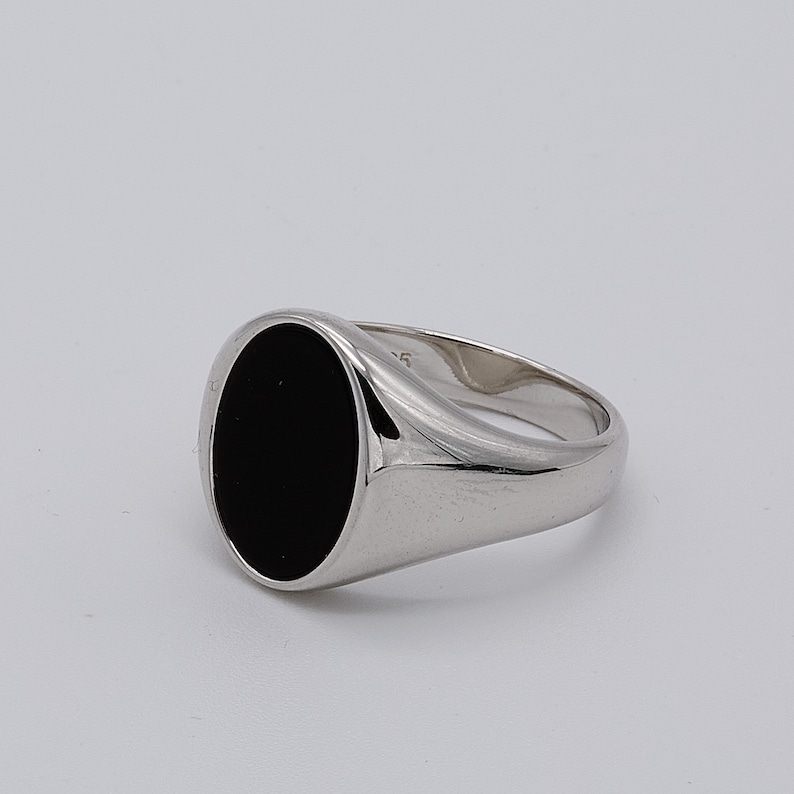 May include: A silver signet ring with a black oval gemstone.