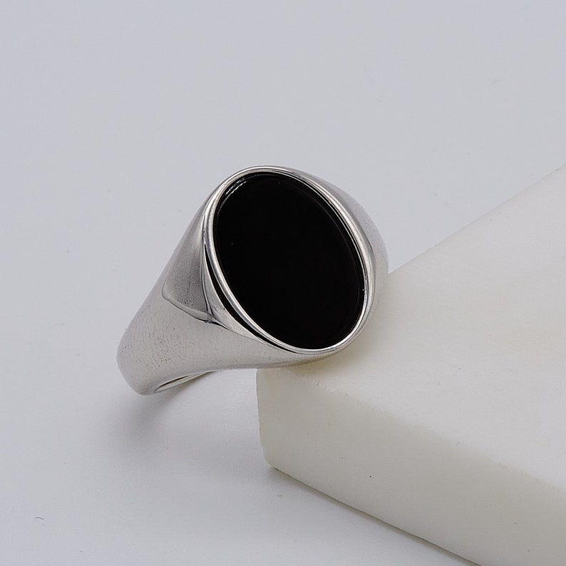 May include: A silver ring with a black oval gemstone.