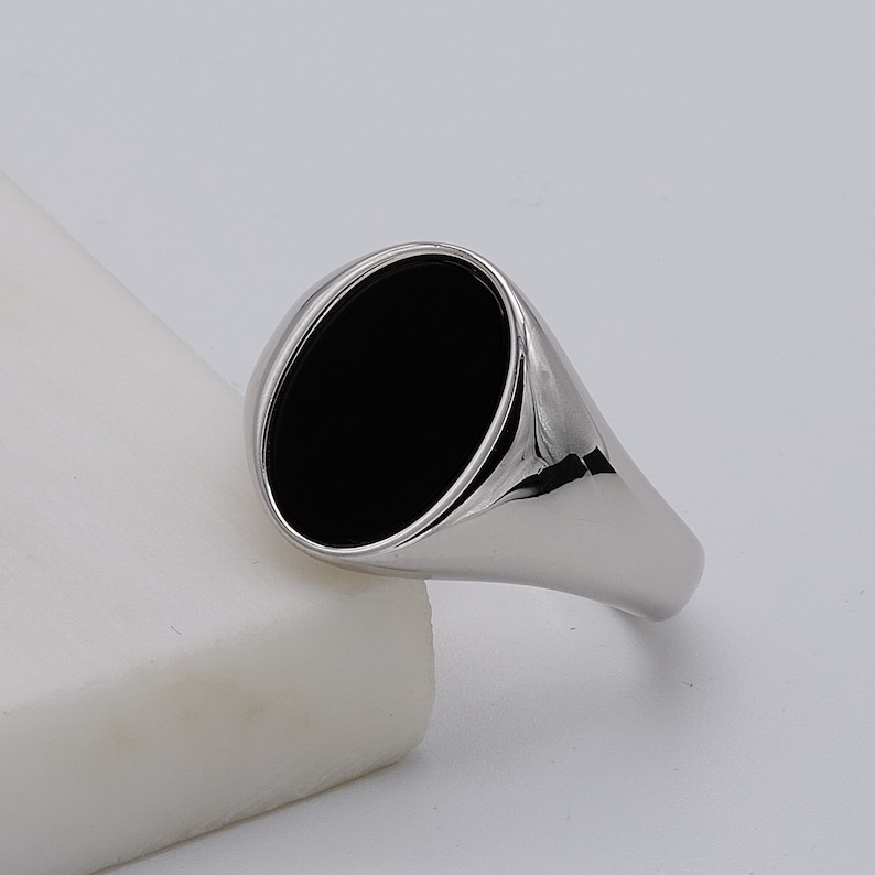 May include: A silver signet ring with a black oval gemstone.