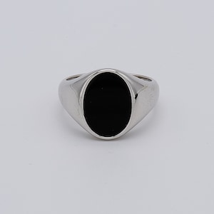 May include: A silver signet ring with a black oval gemstone.