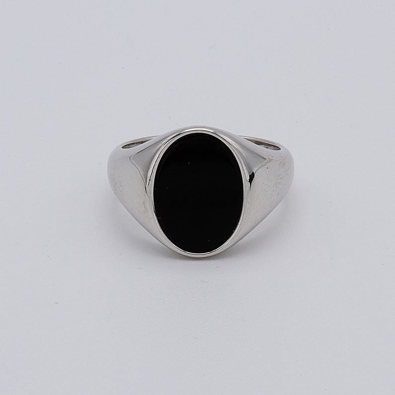 May include: A silver signet ring with a black oval gemstone.
