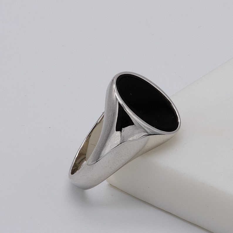 May include: A silver ring with a black oval-shaped stone.