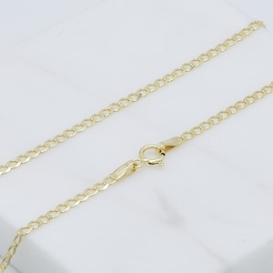 May include: A gold chain necklace with a lobster clasp closure. The chain is made of a curb link pattern.