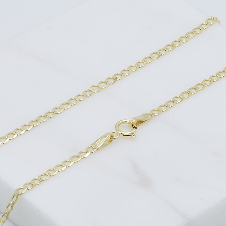 May include: A gold chain necklace with a lobster clasp closure. The chain is made of a curb link pattern.
