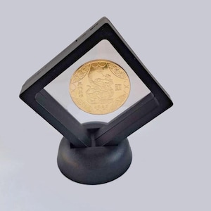May include: A gold coin featuring a Chinese dragon design is displayed in a black diamond-shaped coin holder with a clear acrylic cover. The coin holder has a black base.