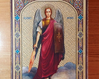 May include: A religious icon depicting the Archangel Michael, a winged figure in a red robe, holding a sword and shield. The icon is framed in a decorative border with gold and blue accents. The text "Св. Михаил" is written in Cyrillic script at the top of the icon.