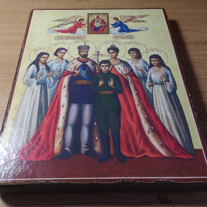 May include: A religious icon depicting a family of saints. The icon features a central image of a king and queen, with their son standing between them. The king and queen are wearing elaborate robes, while the son is dressed in a simple tunic. The icon also includes images of angels and other saints.