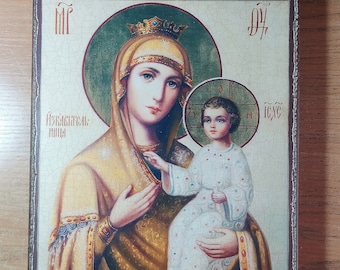 May include: A religious icon depicting the Virgin Mary holding baby Jesus. The icon is painted on a wooden panel with a distressed, aged look. The Virgin Mary is wearing a gold and blue robe with a crown on her head. Baby Jesus is wearing a white robe with a red sash. The icon is framed in a brown wooden frame.