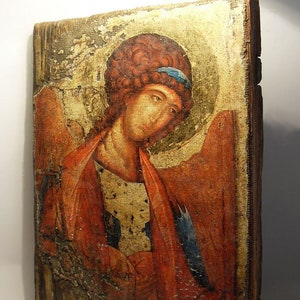May include: An antique icon painting of an angel with red and blue clothing. The icon is painted on a wooden panel and has a distressed, aged appearance.