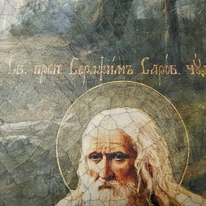 May include: A vintage religious icon painting of a bearded man with white hair, wearing a white robe. The painting is cracked and faded, with a gold halo around the man's head. The text "В. прп. Сергийъ Слбов. Чюдот." is written in gold lettering at the top of the painting.