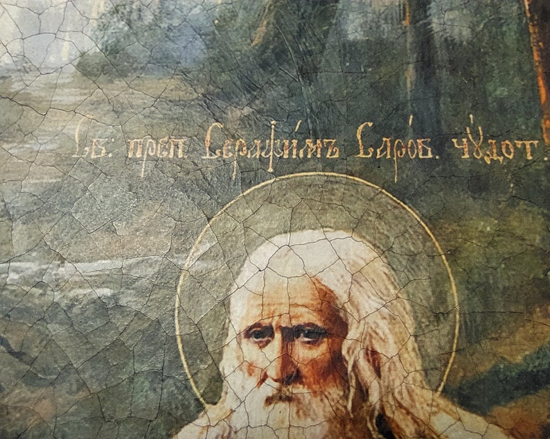 May include: A vintage religious icon painting of a bearded man with white hair, wearing a white robe. The painting is cracked and faded, with a gold halo around the man's head. The text "В. прп. Сергийъ Слбов. Чюдот." is written in gold lettering at the top of the painting.