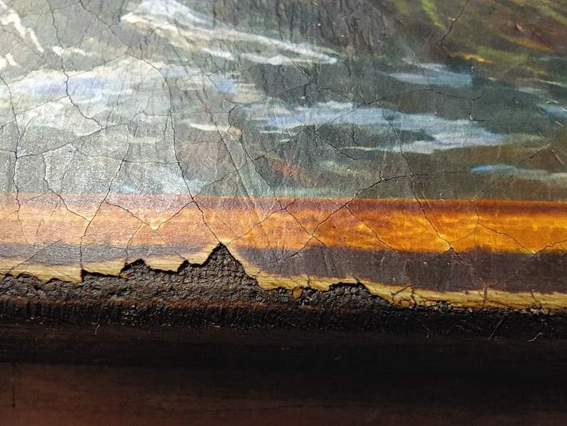 May include: Close-up of a painting's bottom edge, showing a brown wooden frame with a layer of orange paint and a crackled surface.