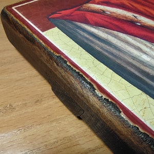May include: Close-up of the edge of a wooden frame with a red and gold border. The frame is painted with a crackled finish and has a distressed look.