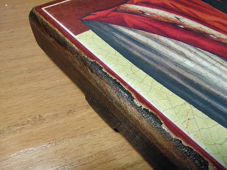 May include: Close-up of the edge of a wooden frame with a red and gold border. The frame is painted with a crackled finish and has a distressed look.