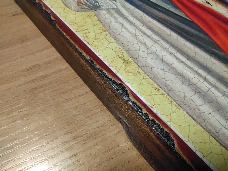 May include: Close-up of the edge of a wooden frame with a red and yellow border. The frame is cracked and shows signs of age.