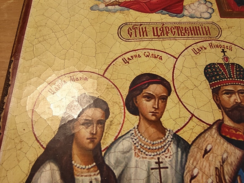 May include: A vintage religious icon depicting a family with the text "СТИ ЦАРСТВЕННЫЙ" (Royal Family) in Cyrillic script. The icon features a woman with a red headband and a pearl necklace, a woman with long dark hair, and a man with a crown and beard. The icon is painted on a cracked, yellow background.