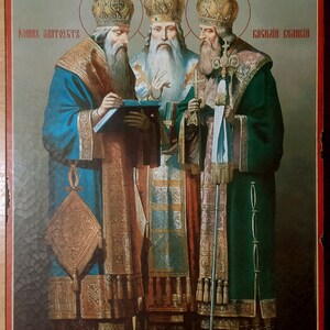 Puede incluir: Un icono que representa a tres hombres con t&uacute;nicas y coronas adornadas. El icono est&aacute; pintado en un panel de madera y presenta el texto "ГРИГОРИЙ БОГОСЛОВ", "КОНСТАНТИН АВТОГУСТ" y "ВАСИЛИЙ ВЕЛИКИЙ".