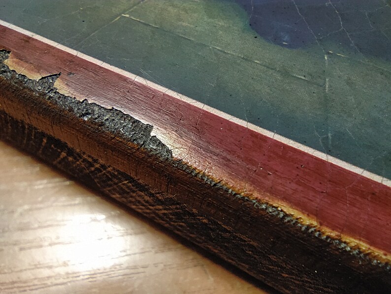 May include: Close-up of a wooden frame with a red and white border. The frame is chipped and worn, showing the wood underneath.