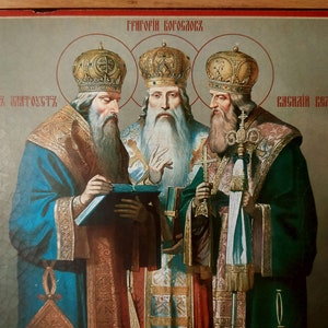 Puede incluir: Un icono religioso antiguo que representa a tres figuras con ropas y coronas adornadas. El icono est&aacute; pintado en un panel de madera y tiene el texto "ГРИГОРИЙ БОГОСЛОВ" en la parte superior y "ЧАСНАЯ ЗАГАДКА" y "ЧАСНАЯ ЕВАНГЕЛИЯ" en la parte inferior.