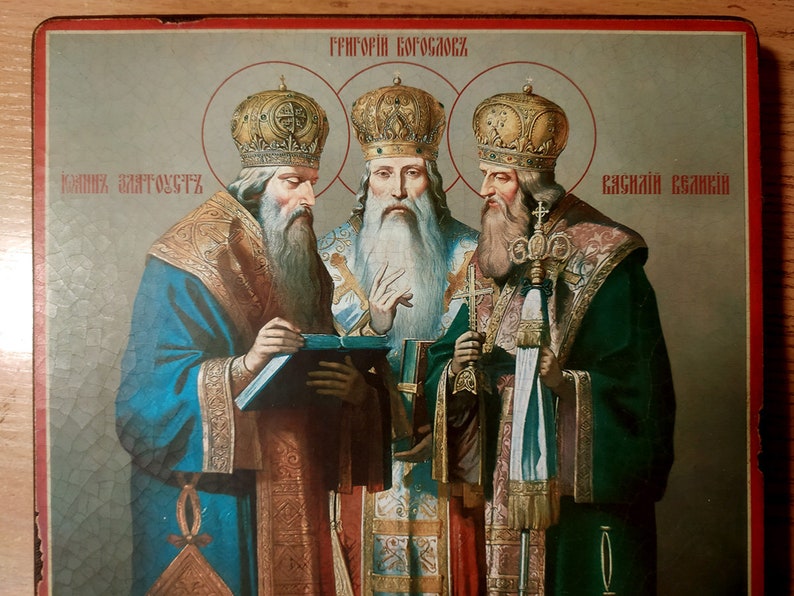 Puede incluir: Un icono religioso antiguo que representa a tres figuras con ropas y coronas adornadas. El icono est&aacute; pintado en un panel de madera y tiene el texto "ГРИГОРИЙ БОГОСЛОВ" en la parte superior y "ЧАСНАЯ ЗАГАДКА" y "ЧАСНАЯ ЕВАНГЕЛИЯ" en la parte inferior.