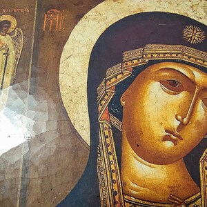 Puede incluir: Un icono vintage que representa a la Virgen Mar&iacute;a sosteniendo a un beb&eacute; Jes&uacute;s. El icono est&aacute; pintado en un panel de madera y tiene un aspecto agrietado y envejecido. La Virgen Mar&iacute;a lleva una t&uacute;nica azul oscuro con ribetes dorados y una corona. El beb&eacute; Jes&uacute;s lleva una t&uacute;nica blanca. El icono est&aacute; enmarcado en un sencillo marco de madera.