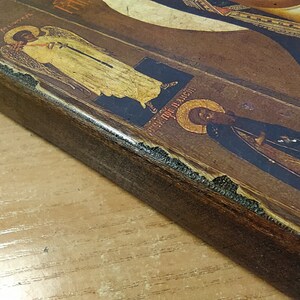 Puede incluir: Un icono enmarcado en madera con una imagen pintada de una figura religiosa. El icono est&aacute; decorado con pan de oro y tiene un acabado desgastado.