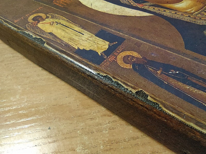 Puede incluir: Un icono enmarcado en madera con una imagen pintada de una figura religiosa. El icono est&aacute; decorado con pan de oro y tiene un acabado desgastado.