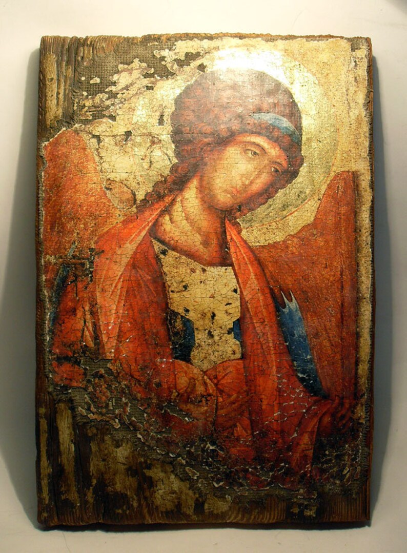 May include: A vintage, wooden icon depicting a religious figure with a red robe and a blue sash. The icon is painted in a traditional style and shows signs of age and wear.