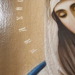 May include: A close-up of a painting of a woman wearing a white veil and a blue robe. The painting is cracked and faded, and the woman's face is obscured by the veil. The text "F.Y.H.S.G." is visible in the upper right corner of the painting.