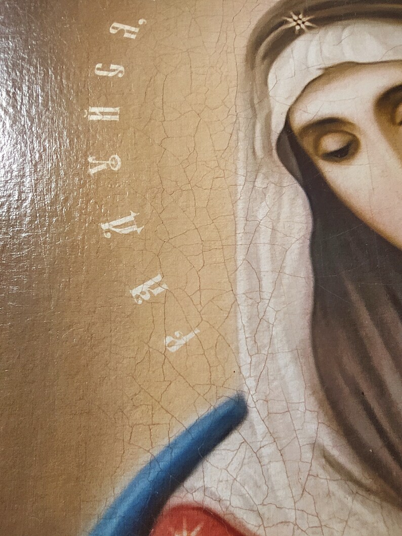 May include: A close-up of a painting of a woman wearing a white veil and a blue robe. The painting is cracked and faded, and the woman's face is obscured by the veil. The text "F.Y.H.S.G." is visible in the upper right corner of the painting.