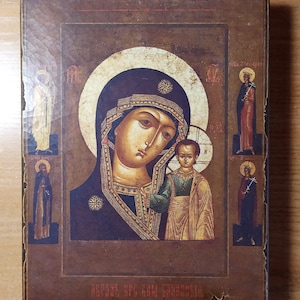 Puede incluir: Un icono religioso de estilo vintage que representa a la Virgen Mar&iacute;a sosteniendo al ni&ntilde;o Jes&uacute;s. El icono est&aacute; enmarcado en un marco de madera oscura y presenta un fondo dorado con detalles intrincados. El texto en la parte inferior dice "ОБОЖЕНИЕ ВСЯКИМ СВЯТЫМ".
