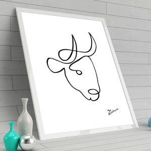 May include: A black and white line drawing of a bull's head with horns, framed in a white frame. The drawing is signed "Picasso" in the bottom right corner.