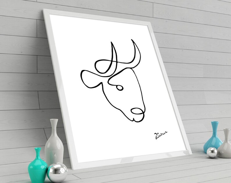 May include: A black and white line drawing of a bull's head with horns, framed in a white frame. The drawing is signed "Picasso" in the bottom right corner.