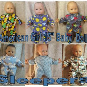 May include: Six baby dolls, each 38 cm tall, wearing long-sleeved footed sleepers with various patterns including ducks, suns, dinosaurs, penguins, a blue grid, and construction vehicles. The text American Girl 15" Baby Doll Sleepers is overlaid.