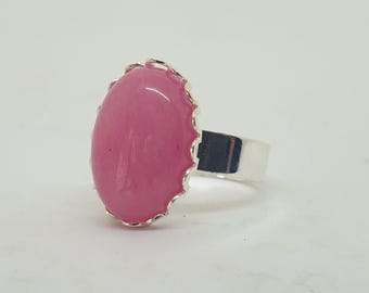 Könnte beinhalten: Ein Ring mit einem ovalen rosafarbenen Edelstein in einer silbernen Fassung. Der Ring hat einen gewellten Rand und eine glatte, polierte Oberfläche.