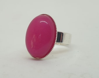 Könnte beinhalten: Ein silberner Ring mit einem großen, ovalen, leuchtend pinkfarbenen Edelstein.