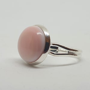 Puede incluir: Un anillo de plata con una piedra redonda rosa y blanca.