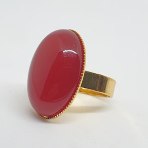Puede incluir: Un anillo de oro con una piedra roja grande de forma ovalada.