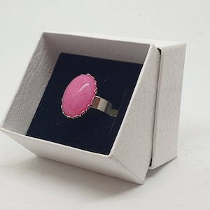 Op de afbeelding: Een roze ovale ring met een zilveren band, gepresenteerd in een witte doos.