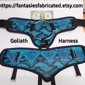 May include: A blue and black snake print harness with a silver ring and adjustable straps. The harness is labeled "Goliath Harness".