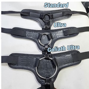 May include: Three black leather harnesses with metal rings, labeled "Standard", "Ultra", and "Goliath Ultra".