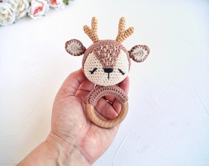 Peut inclure: Un hochet en forme de cerf crochet&eacute;, dans les tons marron, beige et cr&egrave;me. Le cerf a de petits bois, les yeux ferm&eacute;s et une base en anneau de bois. Le hochet est con&ccedil;u pour les b&eacute;b&eacute;s et les jeunes enfants.