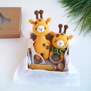 May include: A gift box filled with a crocheted giraffe toy, a wooden giraffe teether, and a yellow crocheted teething necklace.