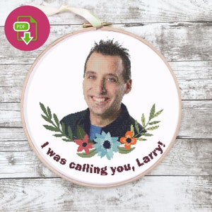 May include: A circular wooden embroidery hoop containing a cross-stitch portrait of a person with short dark hair. Below the portrait are green leaves, red, blue, and orange flowers, and the text "I was calling you, Larry!" in dark brown.