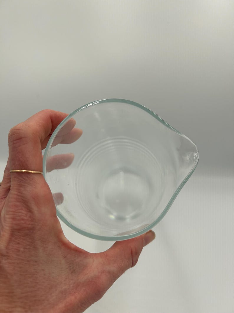 May include: A white ceramic mug with a black handle and the text "But First, Coffee" in a bold, black font. The mug is set against a blurred background, suggesting a cozy setting.