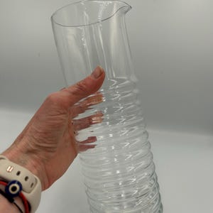 May include: A set of three ceramic mugs with a speckled, matte finish. The mugs are in shades of cream, light gray, and dark gray. Each mug has a simple, minimalist design and a rounded handle. The mugs are stacked on top of each other.