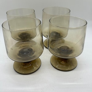 Può includere: Quattro calici in vetro color ambra con una coppa arrotondata e una base corta e circolare. I bicchieri hanno un design semplice ed elegante, adatto per servire bevande. Il design senza stelo offre stabilità.