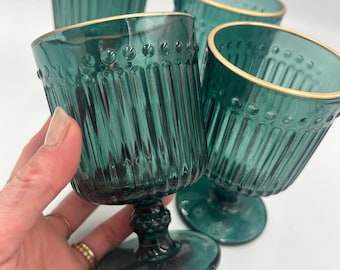 Juego de cuatro copas de vino color turquesa con borde dorado.